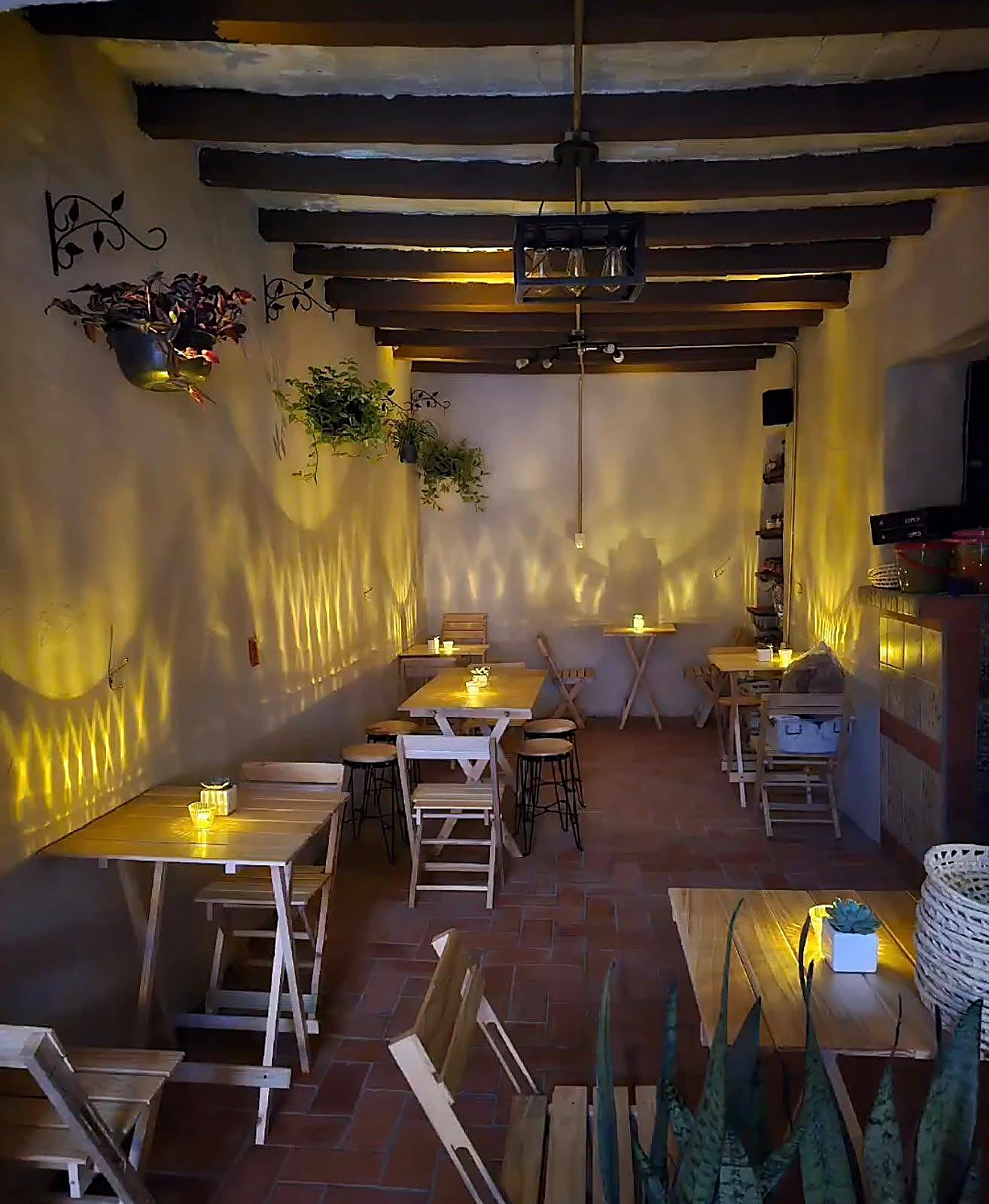 Interior de La Valentina con mesas de madera, vigas y luz cálida de velas