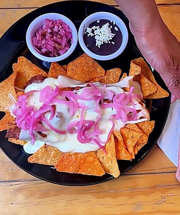Mayita Crujiente: Doritos nacho con cochinita, queso fundido y cebolla morada, servido con frijoles