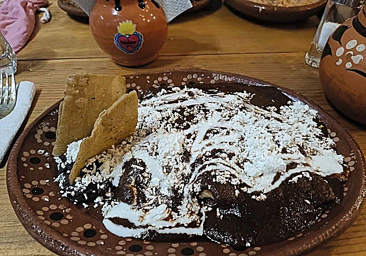 Enmolada bañada en mole de la casa con crema y queso