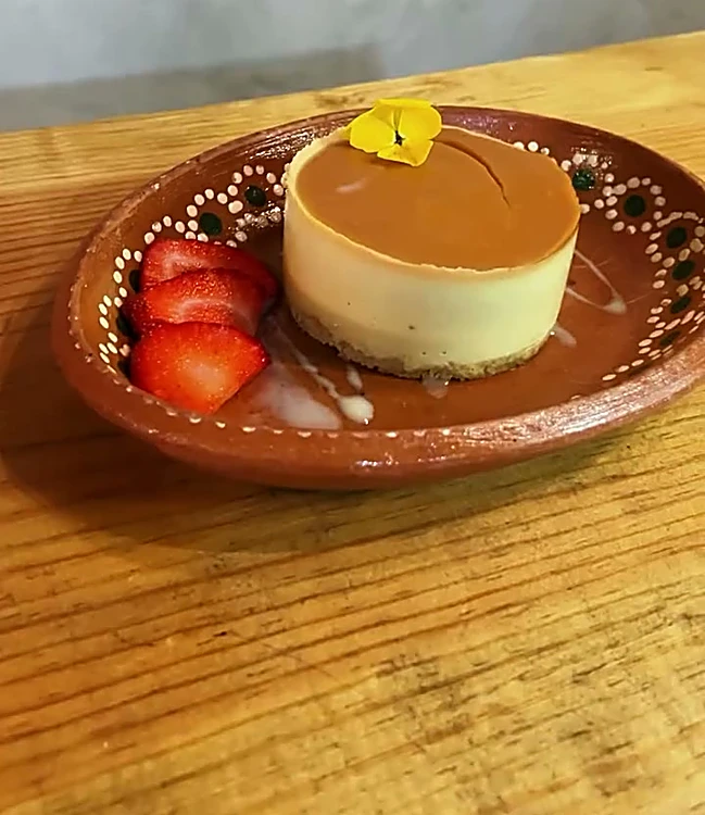 Mousse de guayaba con flor comestible y fresas en plato de barro